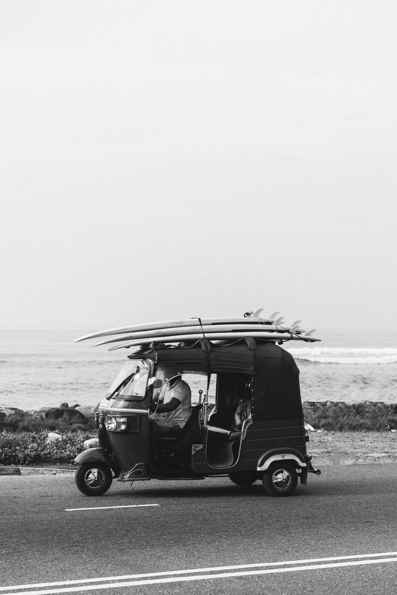 A tuk-tuk loaded with surfboards on the coast road