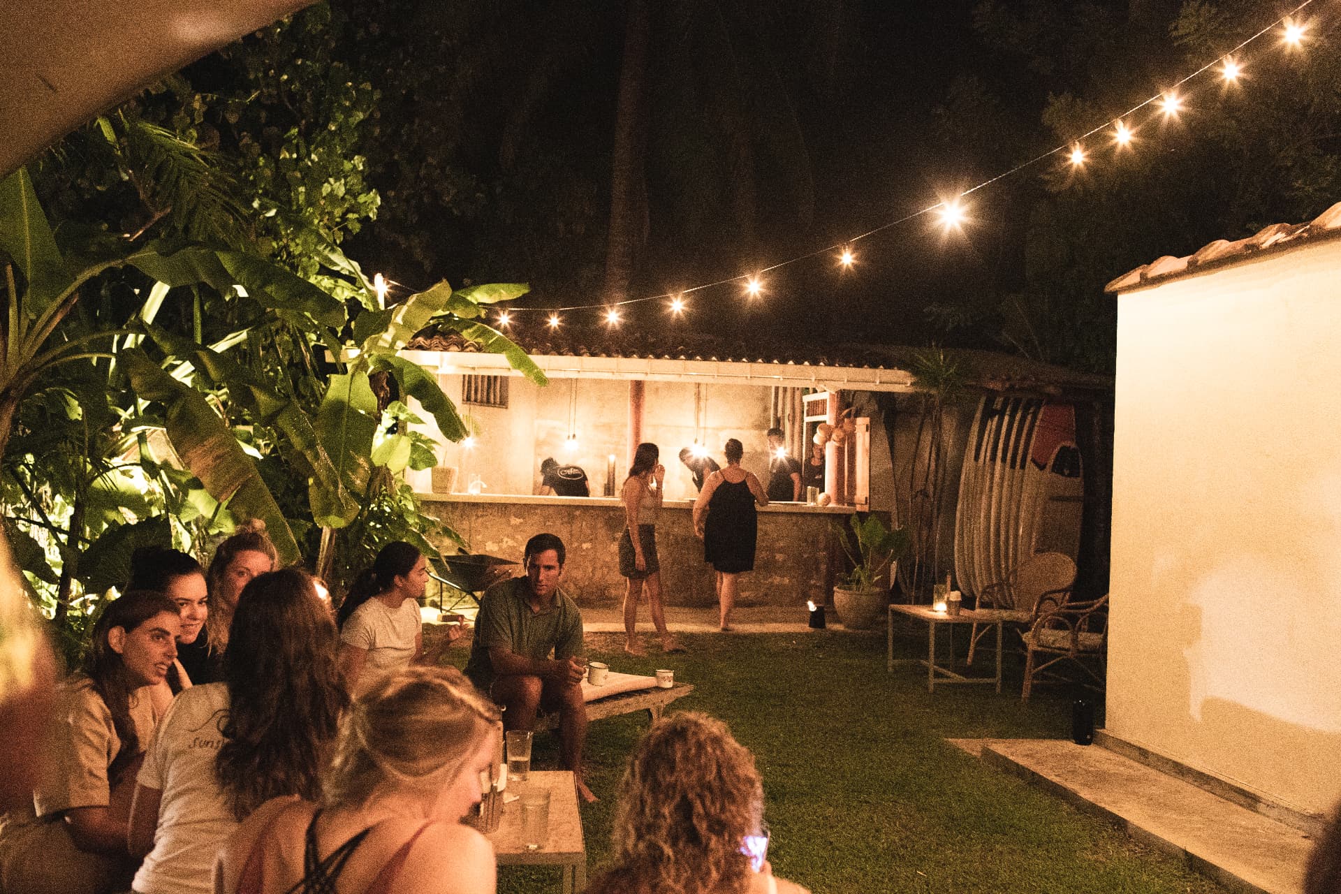 Guests gathered under string lights at the courtyard bar at night