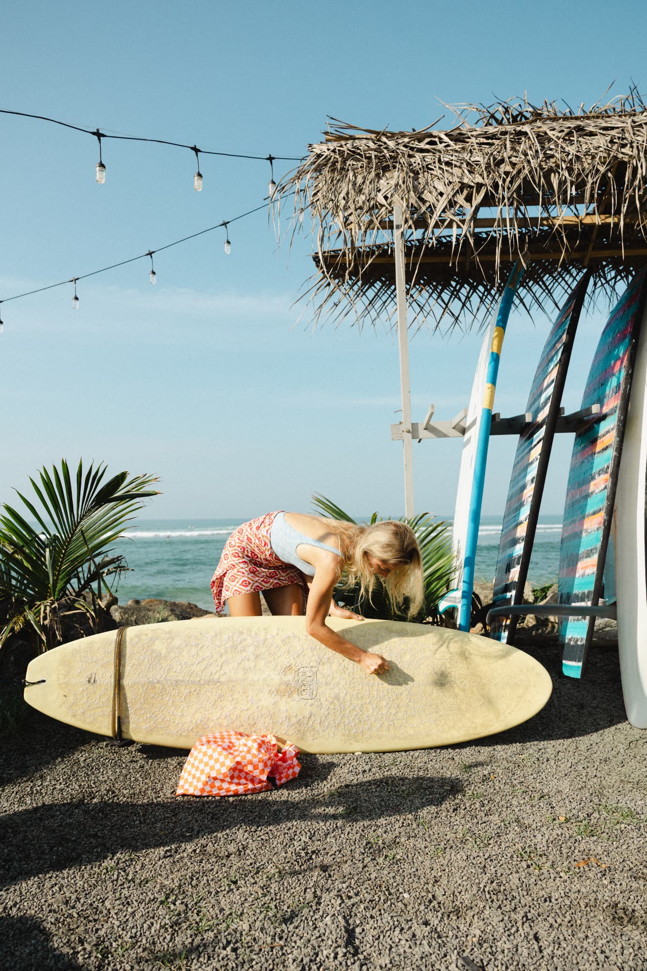 A guest waxing her board under the beach cabana