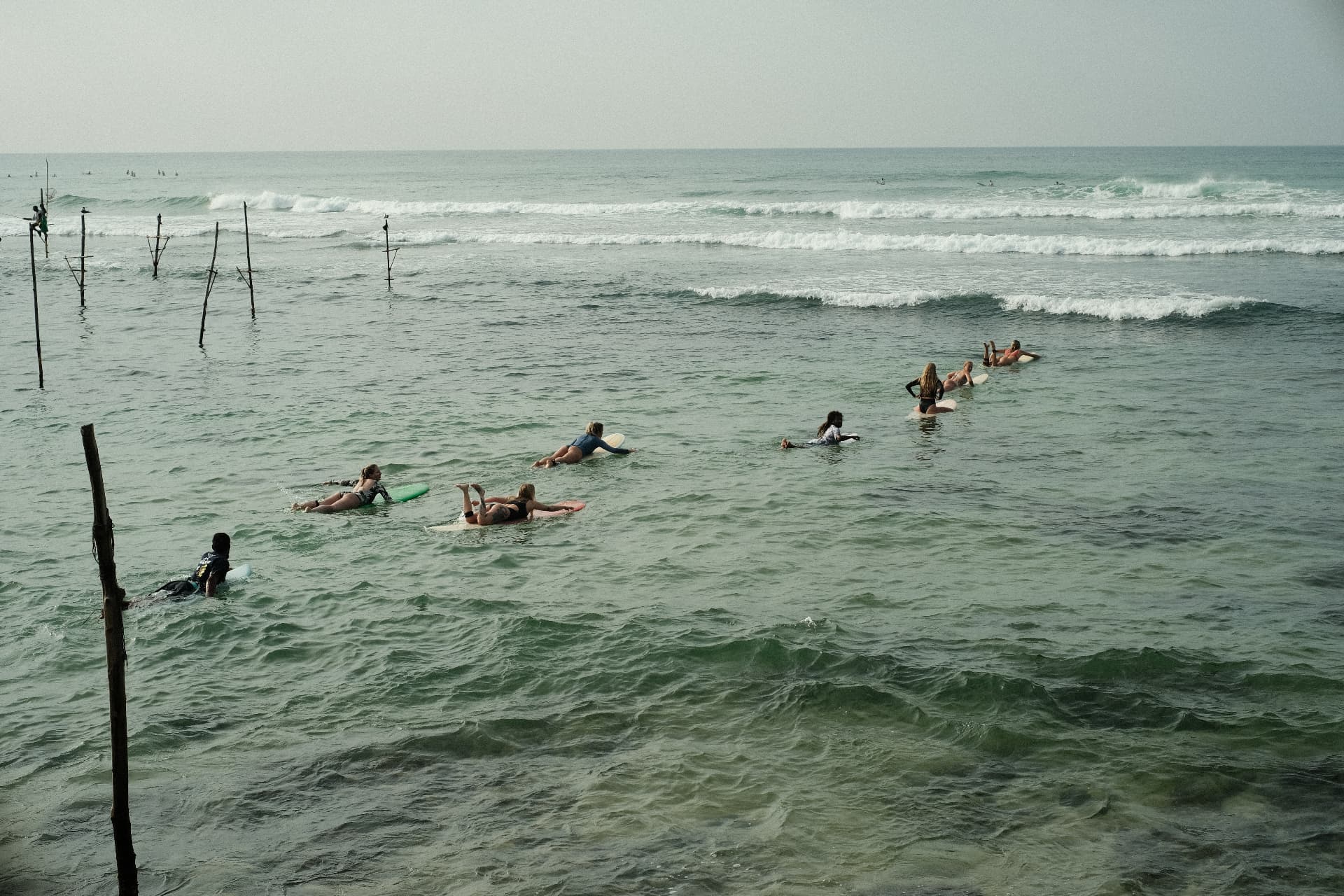 Surfers waiting for waves near the stilt fishermen