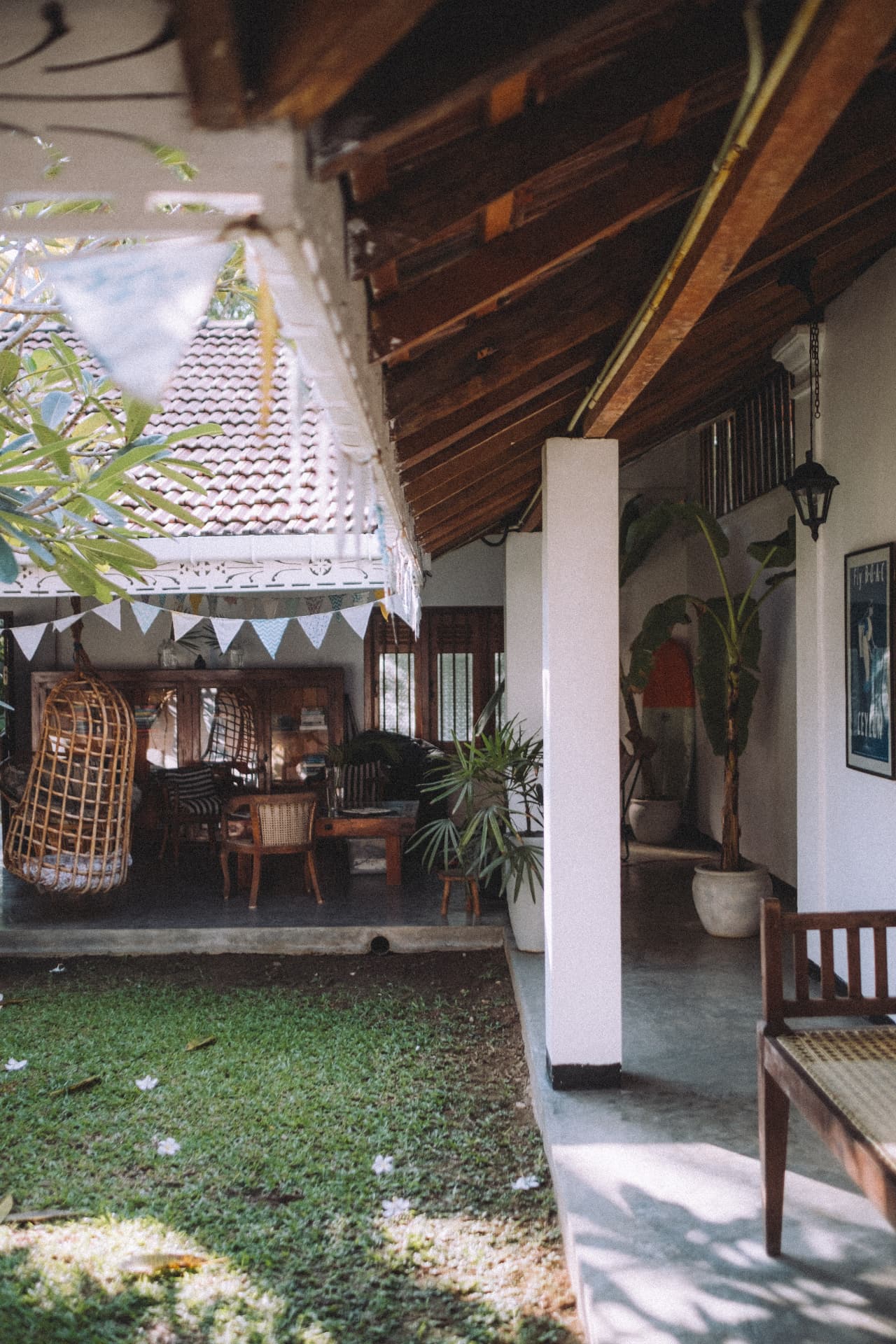 A shaded veranda with wooden beams, hanging chairs and bunting