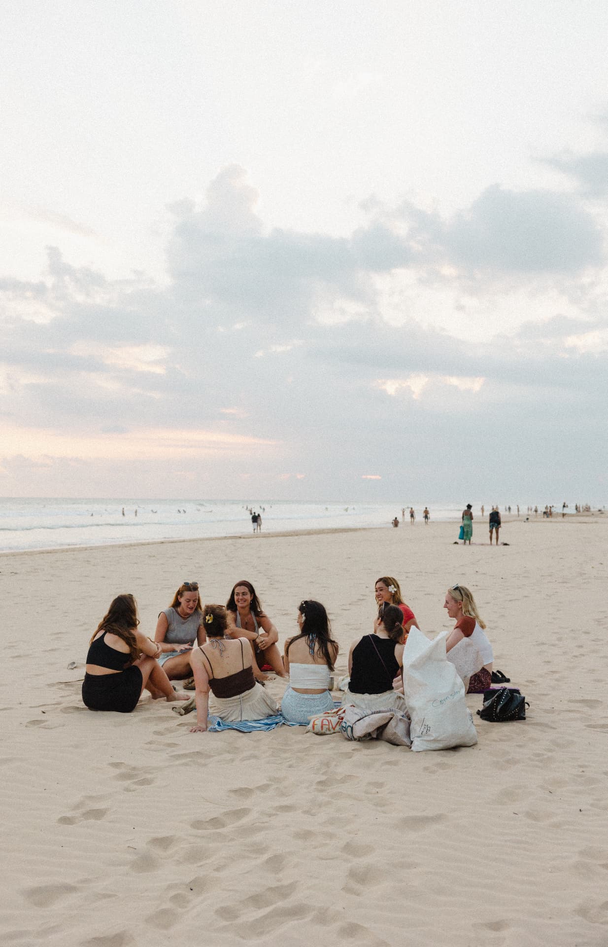 Guests sitting in a circle on the beach at sunset