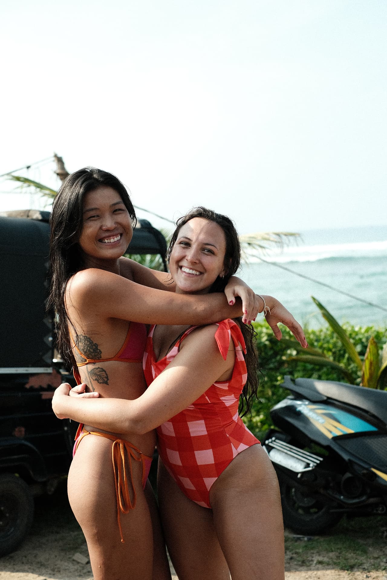 Two smiling guests hugging on the beach beside the ocean