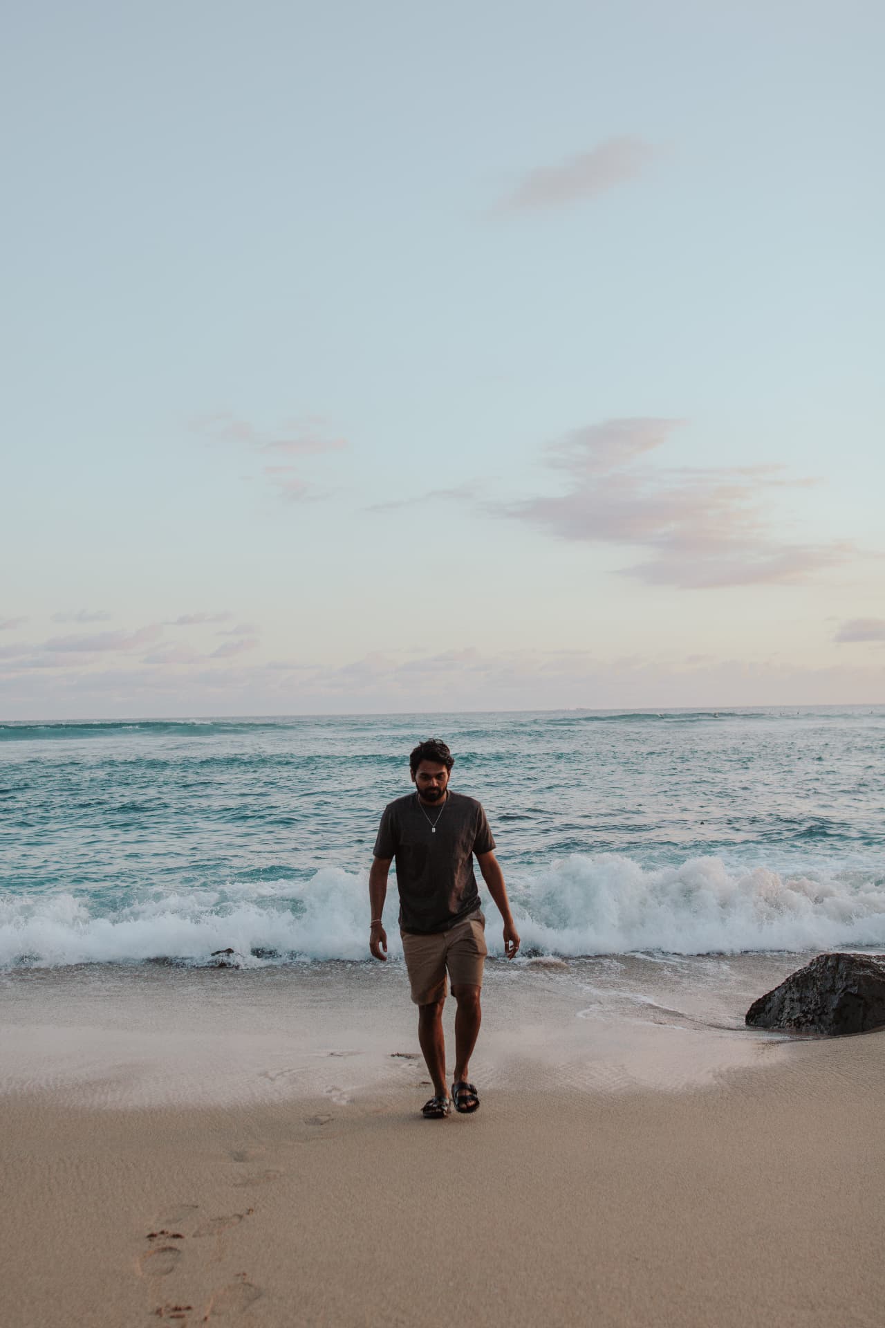 A guest walking along the beach at sunset