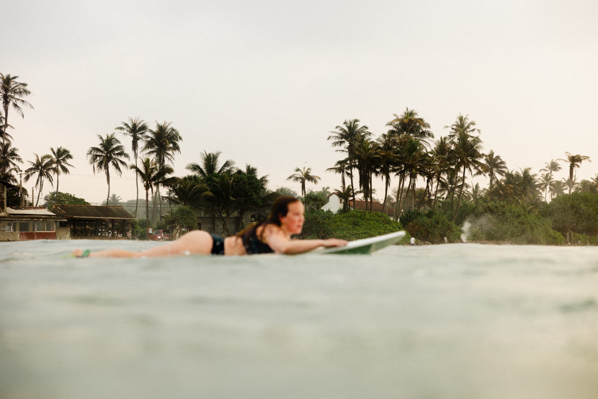 A guest paddling out on her board at sunset