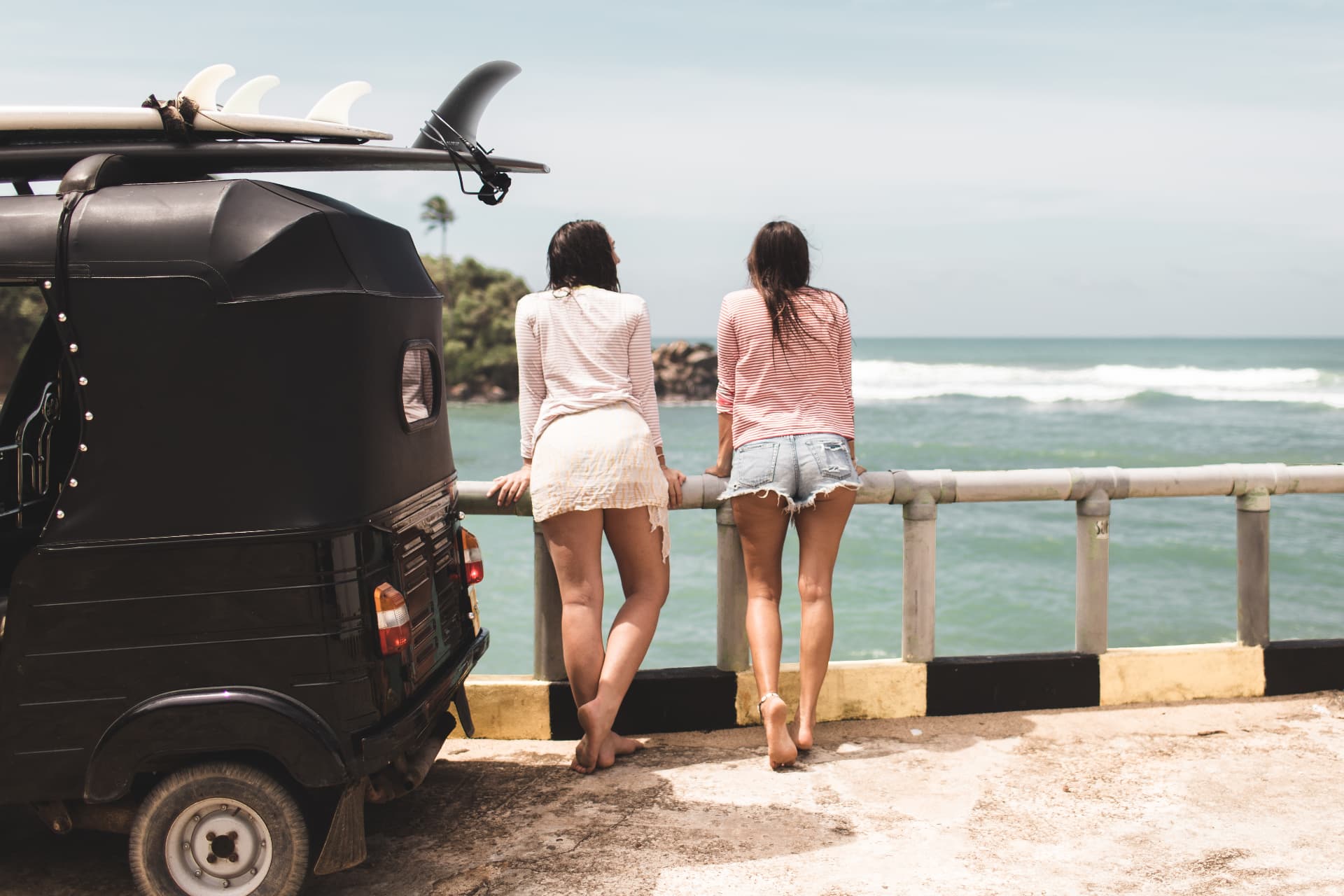 Guests watching the surf from the coast road beside a tuk-tuk