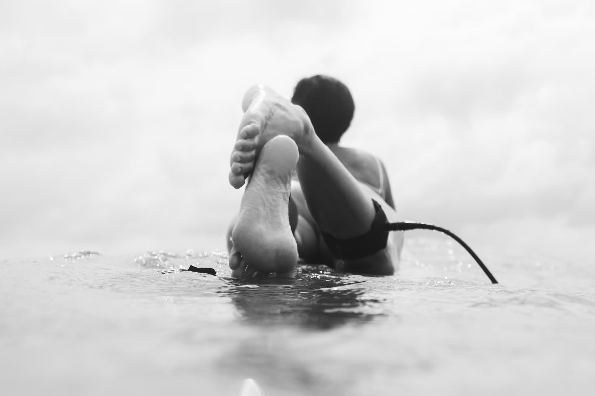 A surfer’s feet balanced on a board from the water