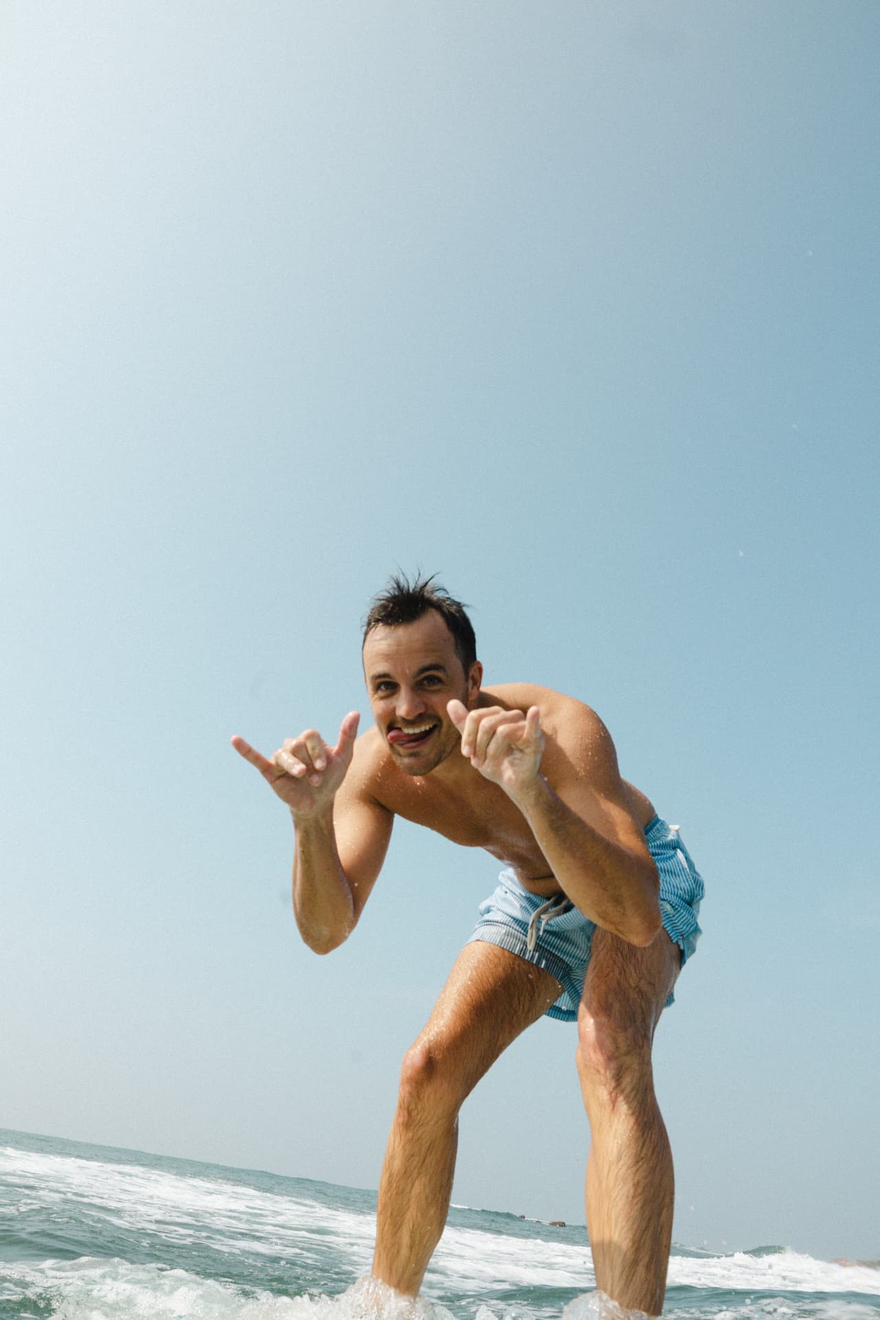 A guest throwing a shaka while riding a wave