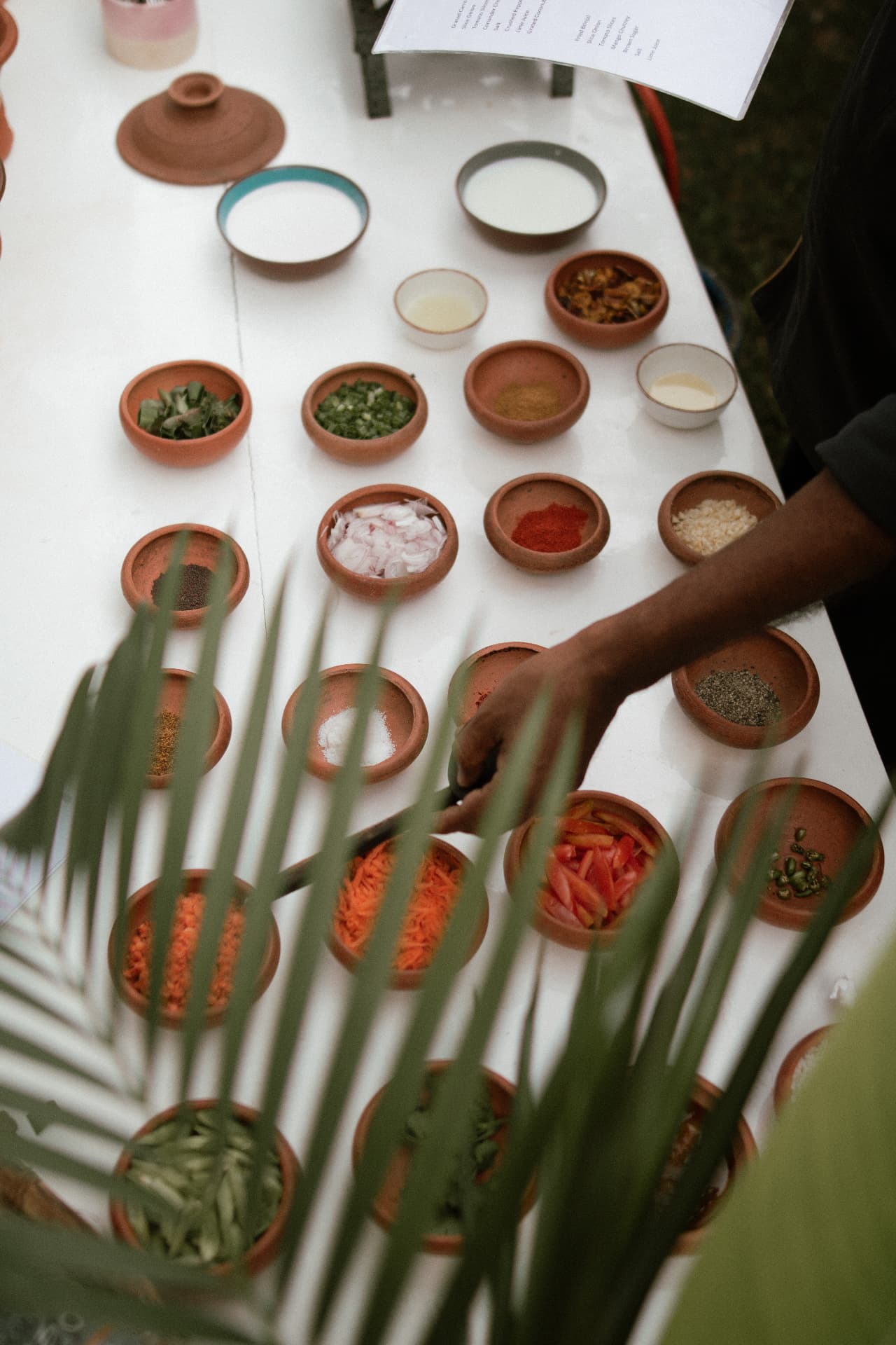 A table laid out with small clay bowls of spices and curry ingredients